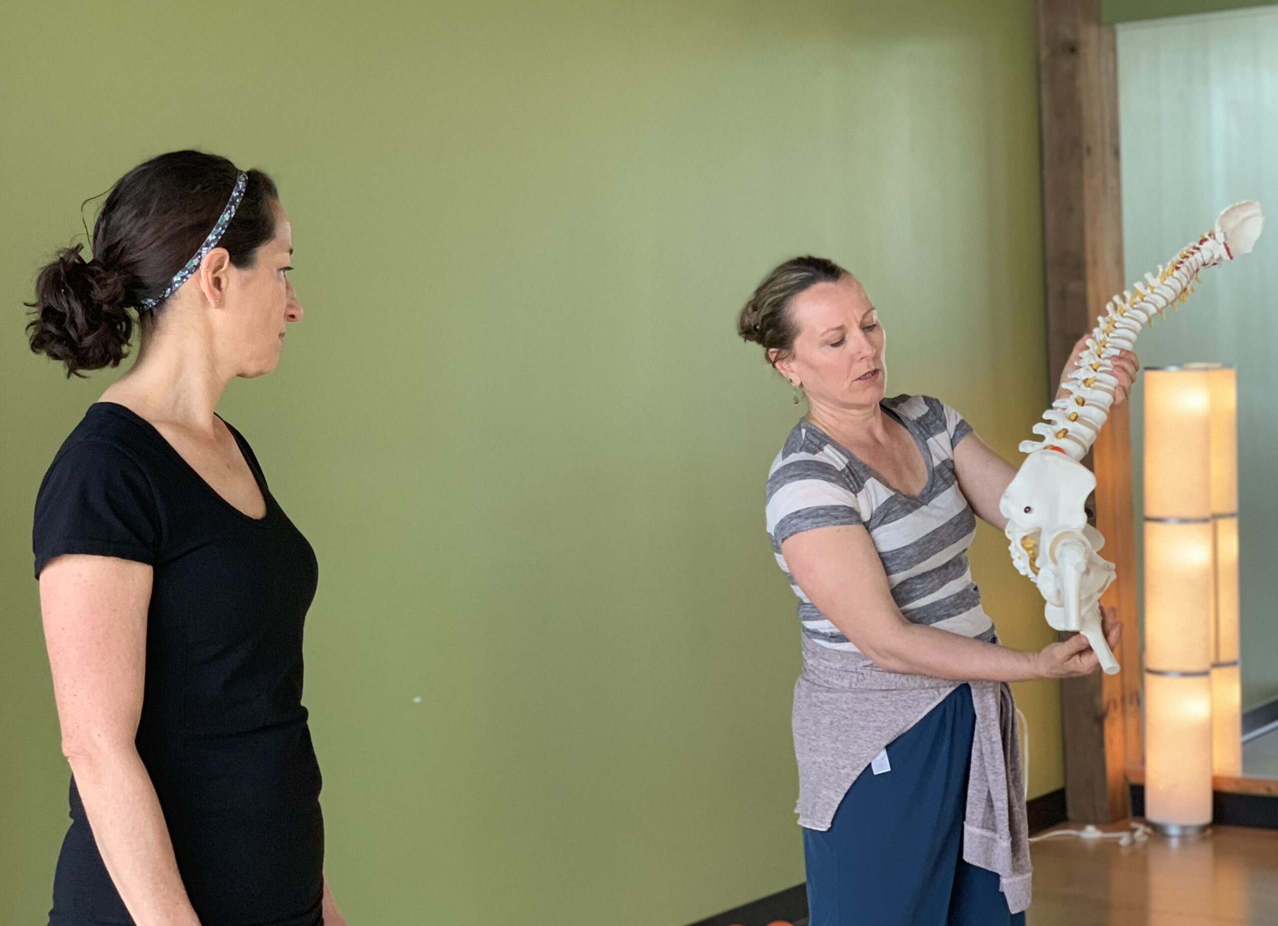A Pilates trainer explaining pelvic anatomy to a client