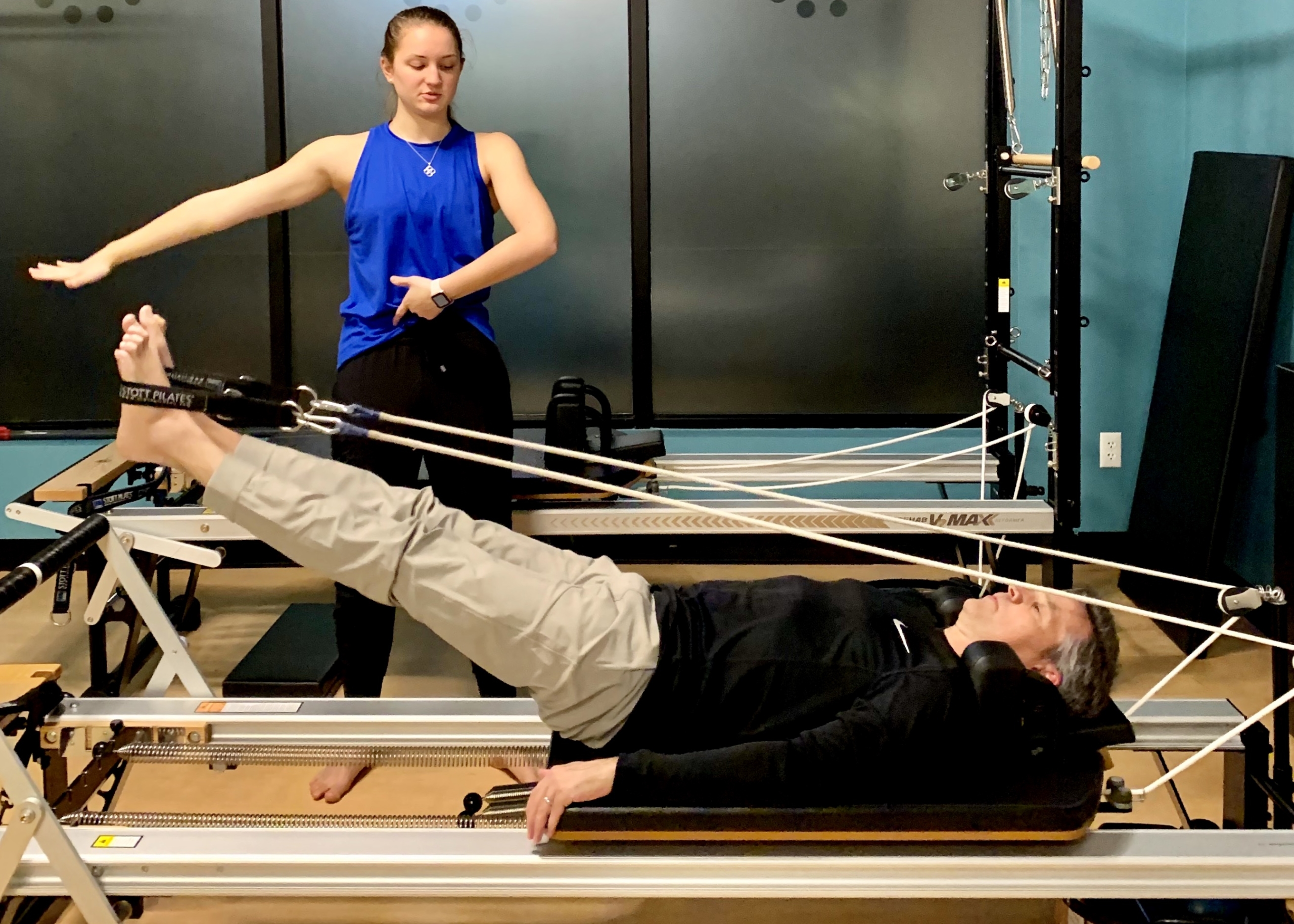 A man working out with a personal trainer on the Pilates Reformer