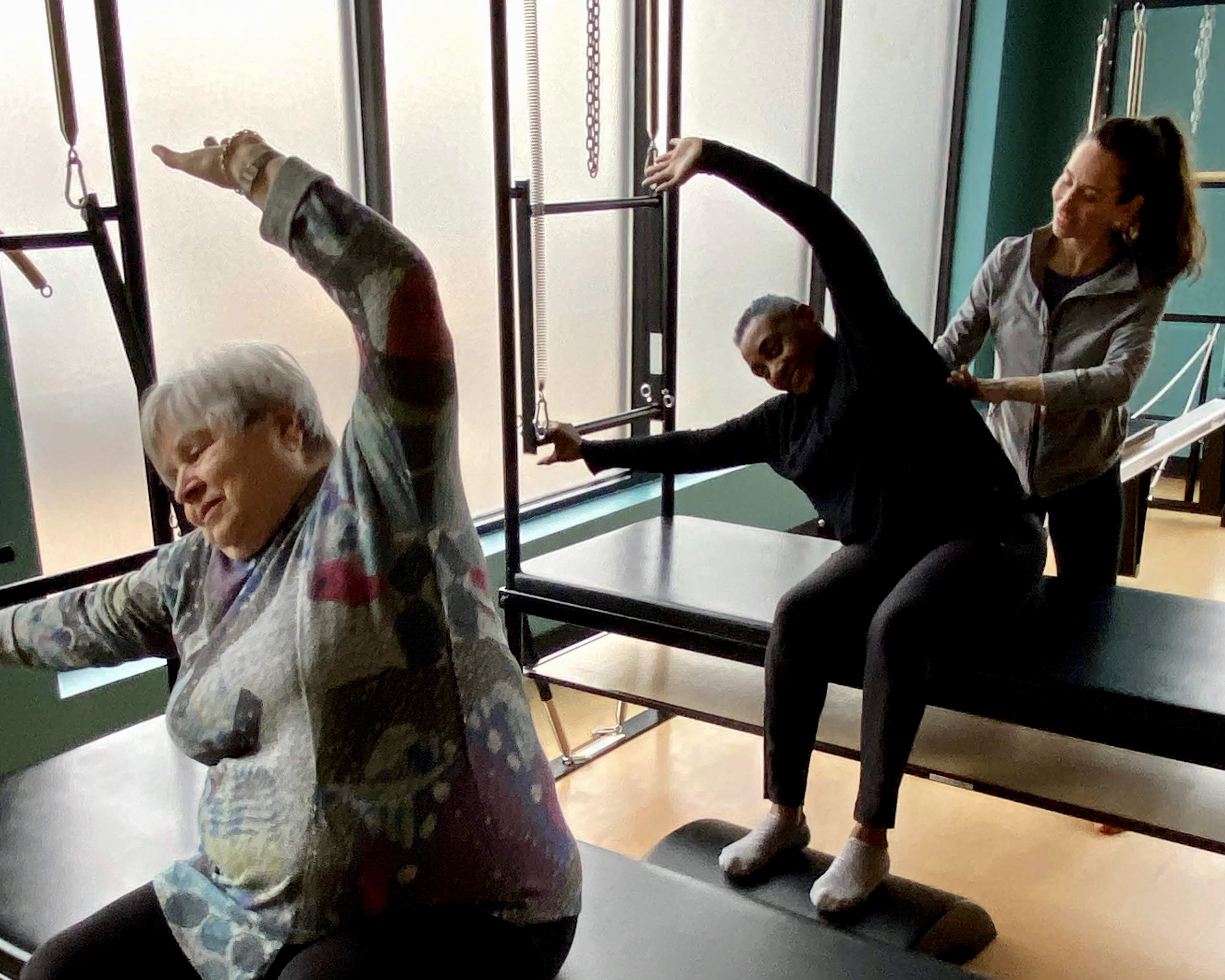 Two Senior Women Doing Pilates With Trainer