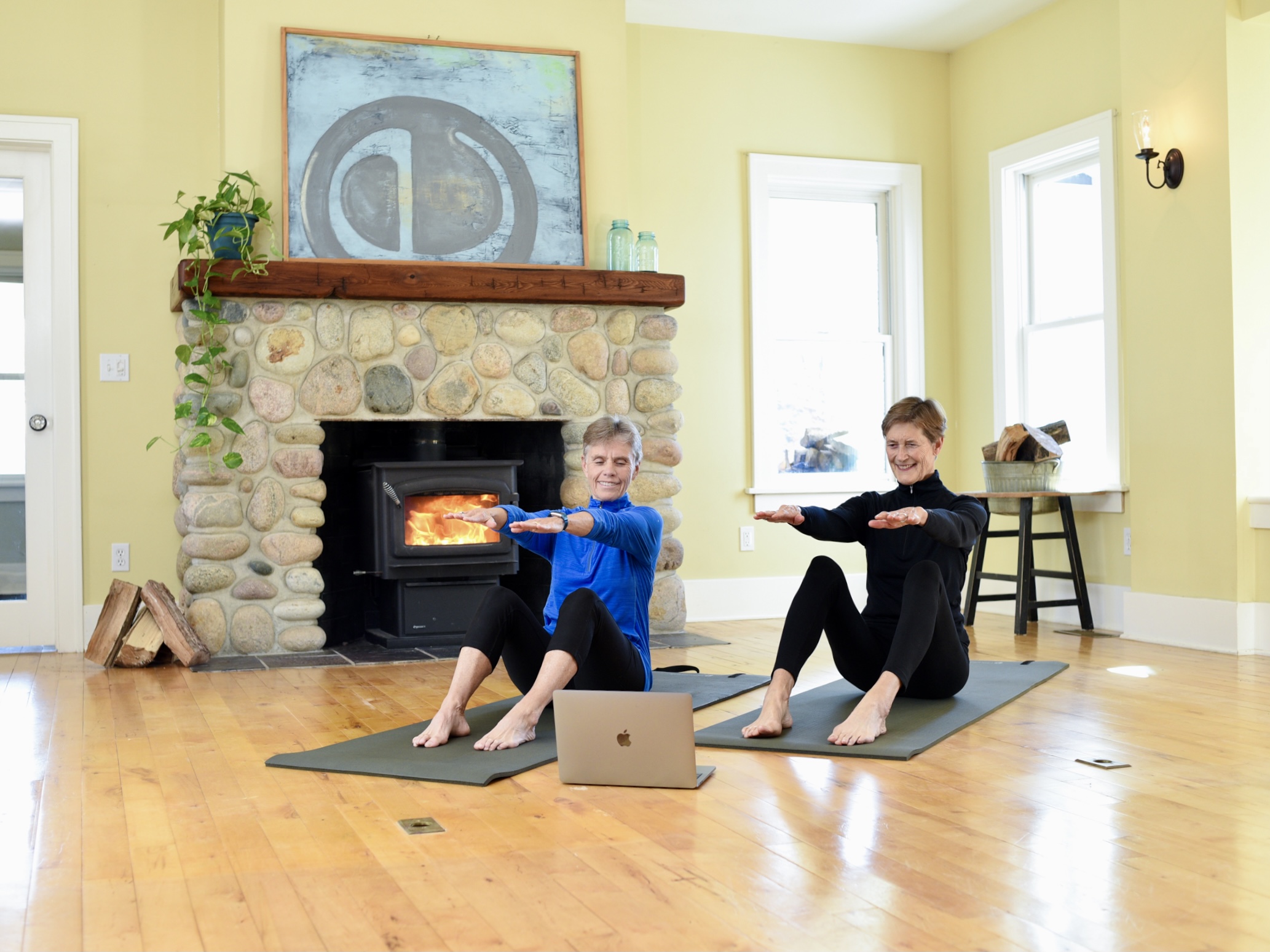 2 women doing online fitness classes on a mat in their living room