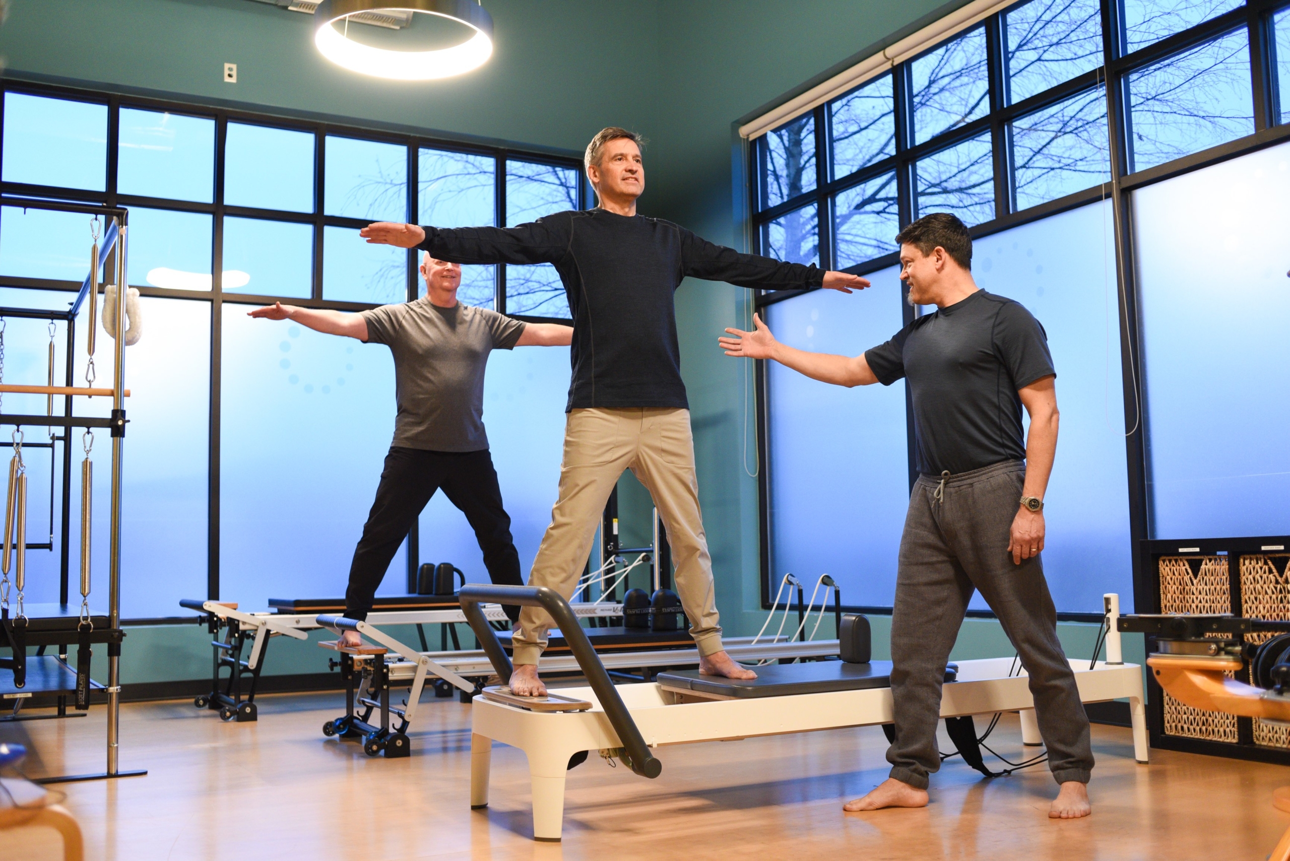 A male Pilates trainer teaching two other men