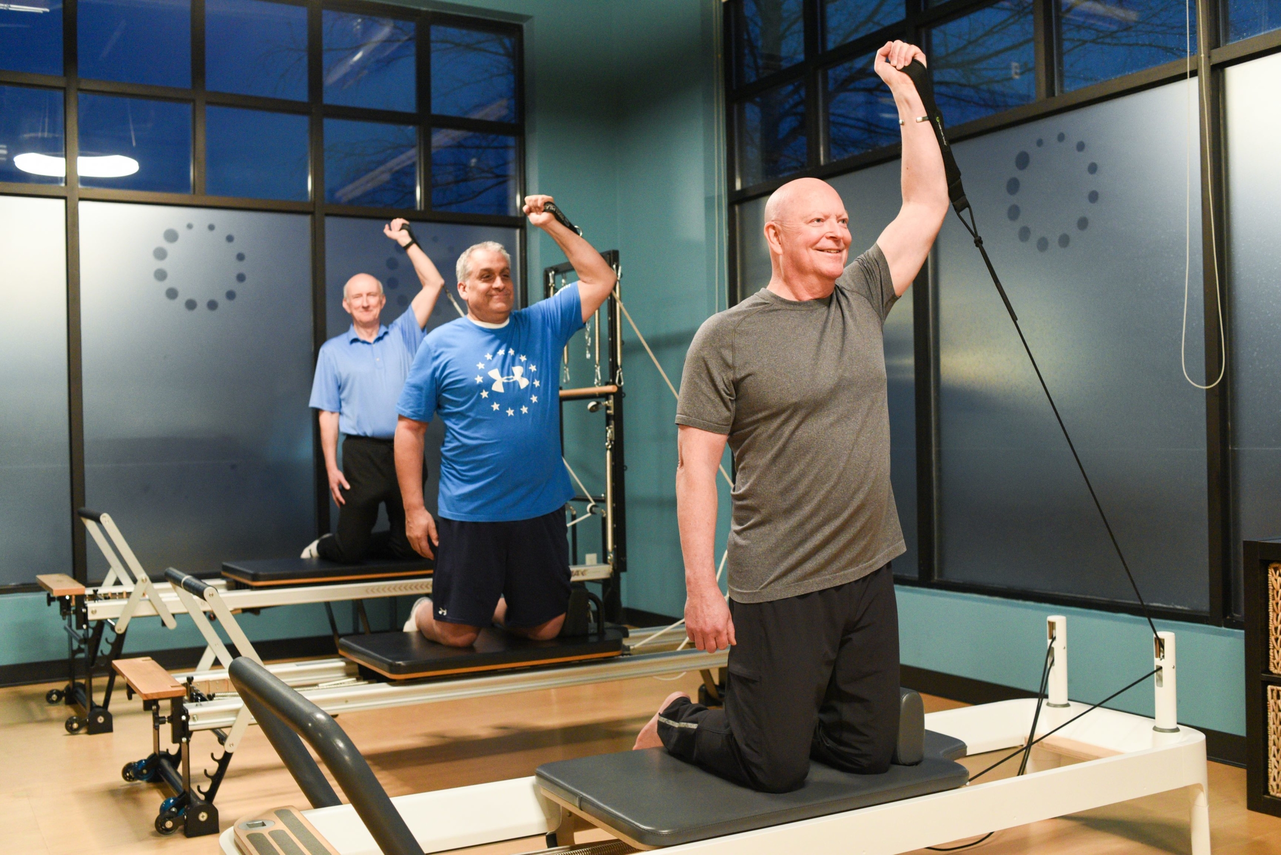3 senior men doing Pilates Reformer arm exercises